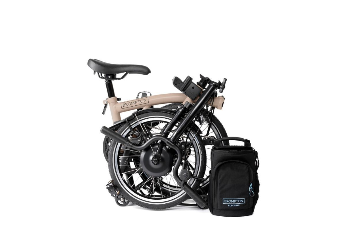 Pale pink Brompton Electric C Line bike folded with luggage bag removed and in front of the bike