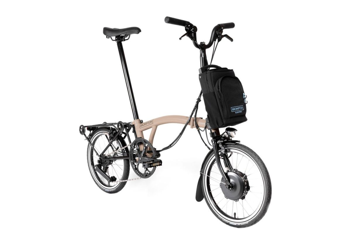 Pale pink  Brompton Electric C Line electric folding bike with luggage bag in the front basket position