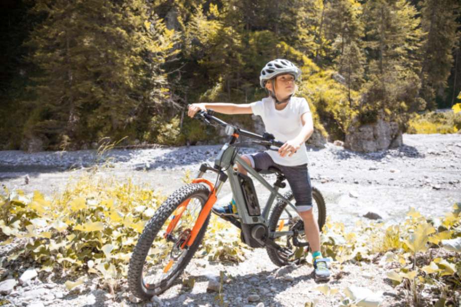 Boy sat on electric bike on slate at the edge of a river